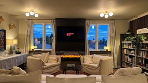A living room with a fireplace, two sofas, a TV, and a bookshelf. - Luxury! Modern `Chic` home off Central Mill Road (Cambridge)