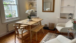 A dining area with a wooden table and chairs, a bench, a white armchair, and a bookshelf. - Amazing Victorian House, Excellent City Location (Cambridge)