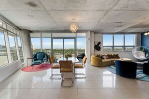 A spacious living area with a round table, chairs, a sofa, and a hanging chair.