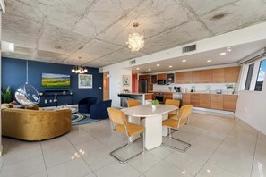A modern kitchen with wooden cabinets, a dining area with a white table and orange chairs, and a living area with a yellow sofa and a round coffee table. - Miami Vice, Chic, Pool and Steps to Midtown Shops (Miami)
