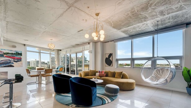 En modern hotellobby med ett stort fönster, en hängstol och ett runt soffbord.