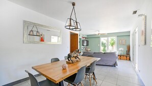 Uma área de refeições com mesa e cadeiras de madeira, luminária pendente e espelho na parede.