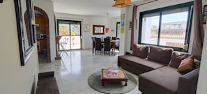 Relax in this stylish living room with a sofa, coffee table, and dining area, offering a view of the outside.