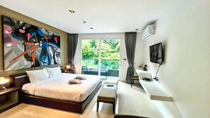 Una habitación de hotel moderna con una cama grande, un escritorio, un televisor y un cuadro en la pared.