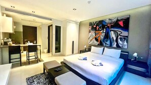 Una habitación de hotel moderna con cama, escritorio, silla y un cuadro en la pared.