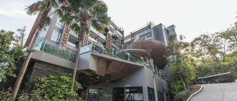 A modern building with a unique architectural design, featuring a curved rooftop and multiple balconies.