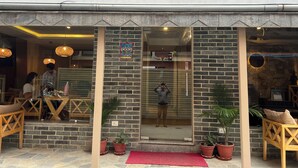 Exterior del Hotel Boutique Bodhi, con fachada de piedra, entrada con puertas de cristal y plantas en macetas.