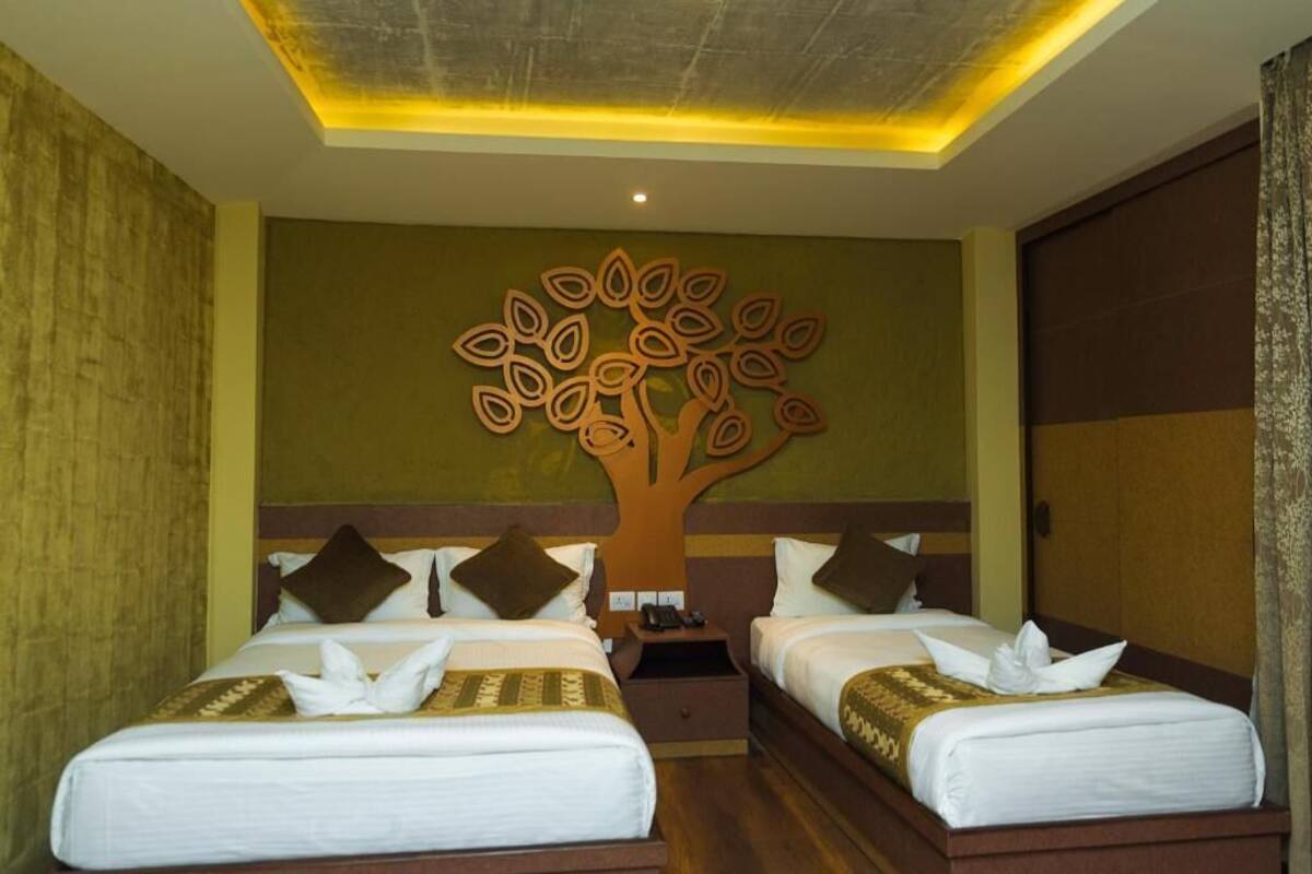 Een hotelkamer met twee bedden, een decoratie aan de muur in de vorm van een boom en een houten hoofdbord.