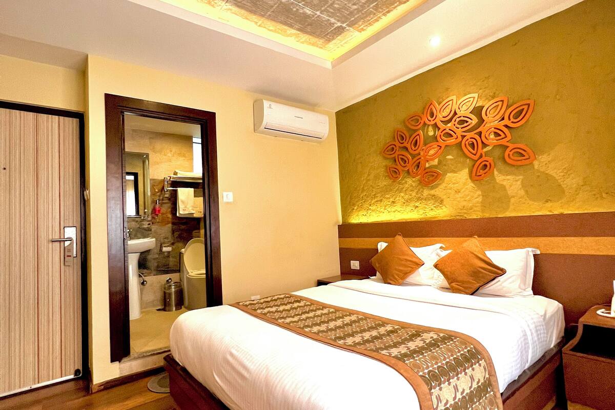 Een hotelkamer met een groot bed, een houten vloer, een plafond met een structuur en een wandairconditioner.