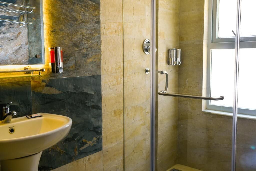 Un baño con cabina de ducha de vidrio, un lavamanos y un espejo.