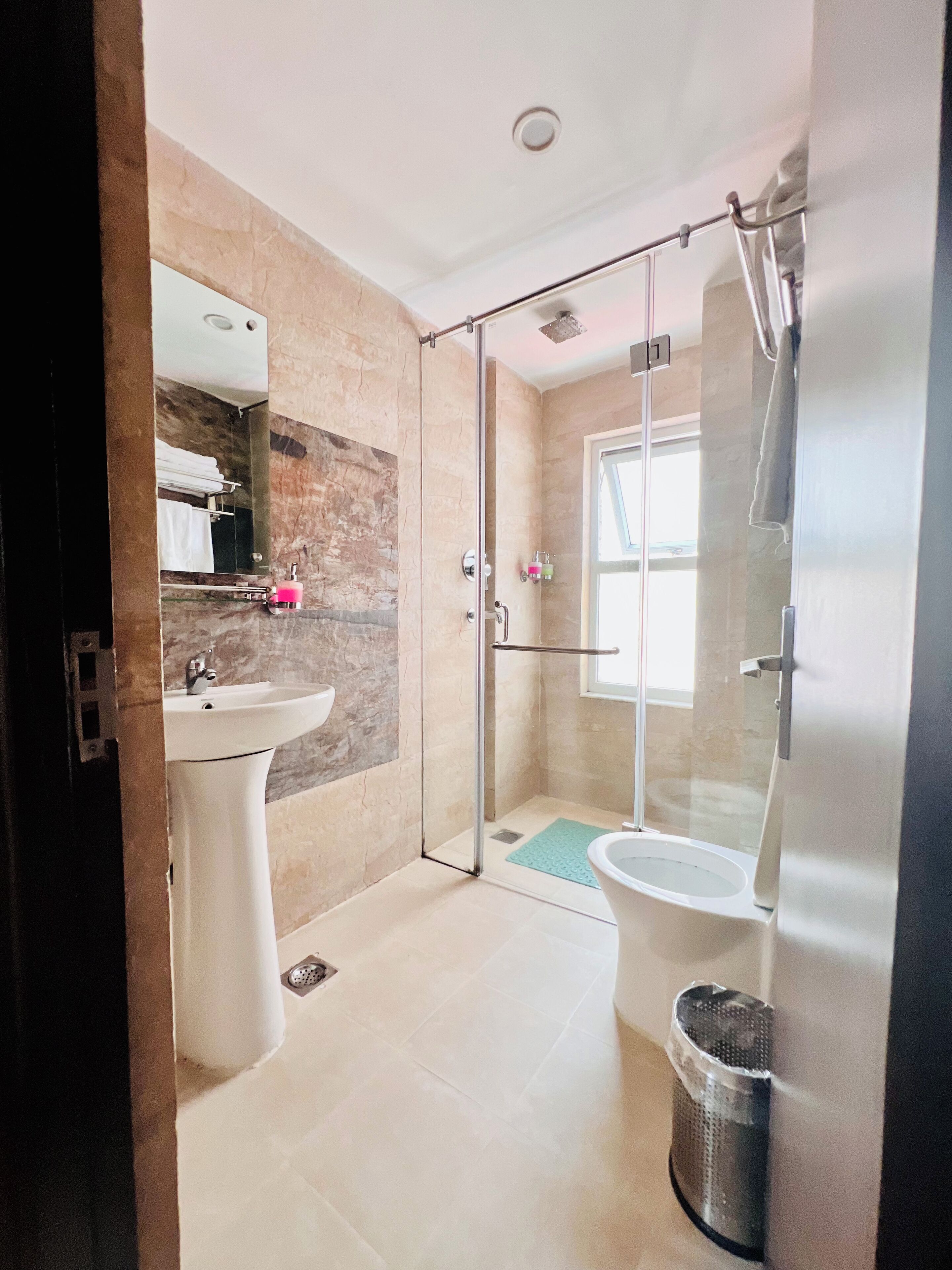 Une salle de bain moderne avec une douche à parois de verre, un lavabo sur colonne et des toilettes.