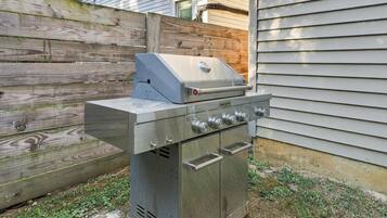 A stainless steel outdoor grill with a built-in smoker, a side burner, and a vented cabinet.
