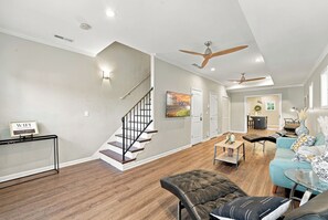 Un salon moderne avec un escalier, un ensemble de canapés et un coin repas.