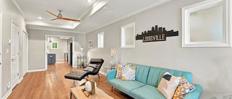 A spacious living room with a teal sofa, a coffee table, and a ceiling fan.
