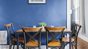 A dining area with a blue wall, a framed picture, and a table with chairs. - 3BR Relaxing Home in Louisville's Prime Location! (Louisville)