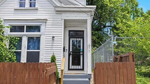 A white house with a black front door, wooden gate, and a small porch. - 3BR Relaxing Home in Louisville's Prime Location! (Louisville)