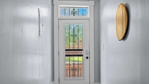 A white door with a glass panel and a decorative metal design, leading to a wooden deck. - 3BR Relaxing Home in Louisville's Prime Location! (Louisville)