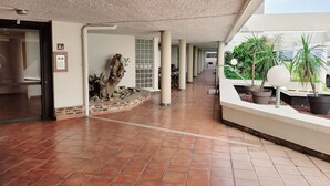 A spacious corridor with tiled flooring, a wooden sculpture, and potted plants. - Canet-en-Roussillon - 1-BR Alcove - 4 ppl - Parking - Loggia - Elevator - 1 star (Canet-en-Roussillon)