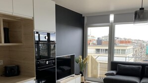 Een modern appartement met een keuken, woonkamer en een groot raam met uitzicht over de stad.