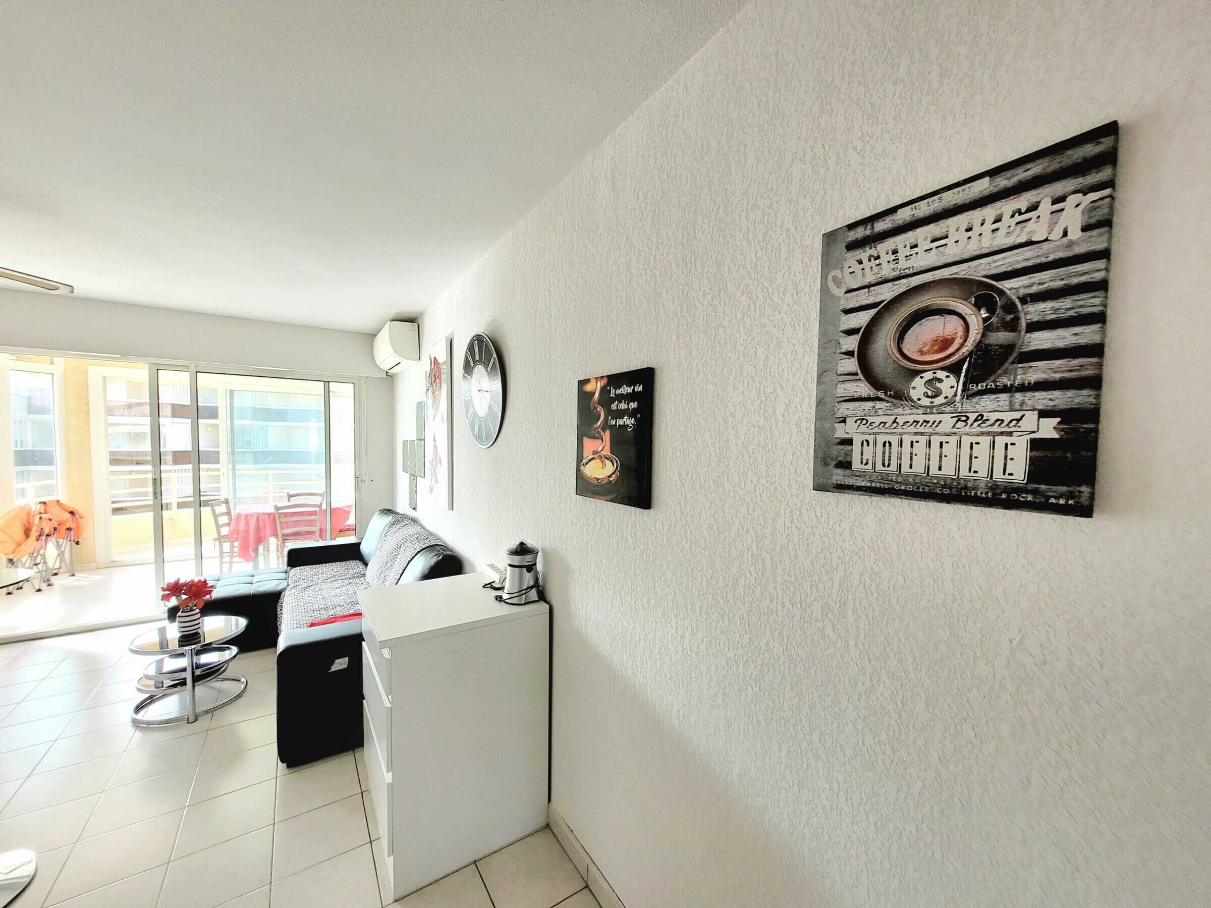 A modern kitchen with a refrigerator, a coffee machine, and a dining area with a table and chairs.