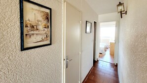 Un pasillo con un cuadro enmarcado de un edificio histórico, una puerta y una lámpara.