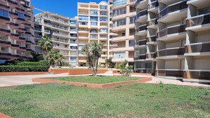 A residential building complex with multiple balconies, a grassy courtyard, and a brick pathway. - Canet-en-Roussillon - Studio 2 pers - Sea view - Quiet residence (Canet-en-Roussillon)