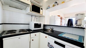 A compact kitchen with a microwave, toaster, stove, and dishwasher. - Canet - T2 cabin, 5 pers, beach access, pool, parking (Canet-en-Roussillon)
