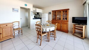 A compact living space with a dining area, kitchen, and a television. - Canet - T2 cabin, 5 pers, beach access, pool, parking (Canet-en-Roussillon)