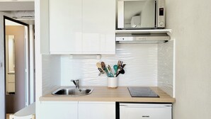 Una cocina compacta equipada con microondas, lavaplatos y fregadero.