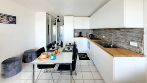 A modern kitchen with white cabinets, a wooden countertop, and a tiled backsplash. - Canet-en-Roussillon - 6 ppl - T3 - Beach Access, Parking, Pool, Wifi (Canet-en-Roussillon)