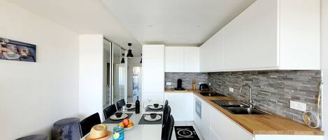A modern kitchen with white cabinets, a wooden countertop, and a tiled backsplash.