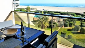 A balcony with a table, a bowl, and a wine glass. The balcony overlooks a beach and a pool area. - Canet-en-Roussillon - 6 ppl - T3 - Beach Access, Parking, Pool, Wifi (Canet-en-Roussillon)