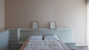 Een slaapkamer met een bed, een nachtkastje, een kledingkast en twee aan de muur bevestigde fotolijstjes met tekst.