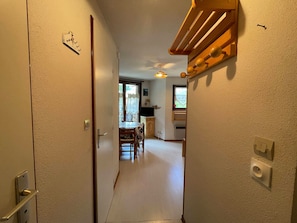 Enter a cozy space leading to a dining area with a table and chairs, and a kitchen with a window.