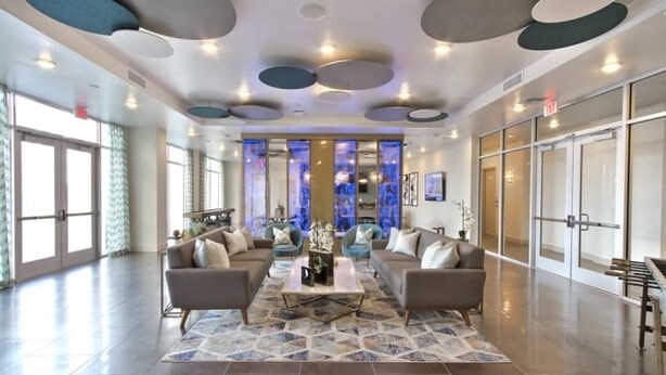 A spacious lobby with a central seating area, large windows, and a modern ceiling design. - Landing | Stunning 1BD, Gym, Clubhouse (Las Vegas)