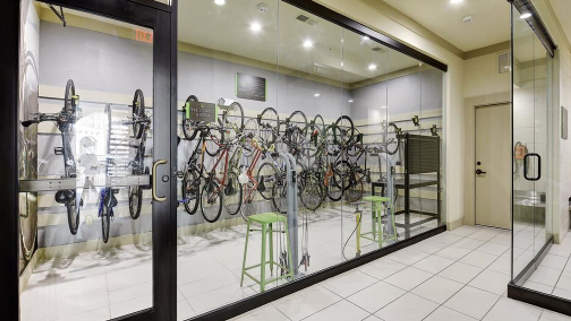 A bike rental station with multiple bicycles and a glass wall.