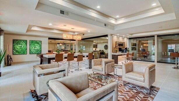 Amplia sala de estar con muebles modernos, comedor y cocina visibles a través de paredes de vidrio.
