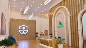 A reception area with a wooden reception desk, a reception counter, and a logo on the wall. - VinaEcolife Lodge (Tan Xuan)