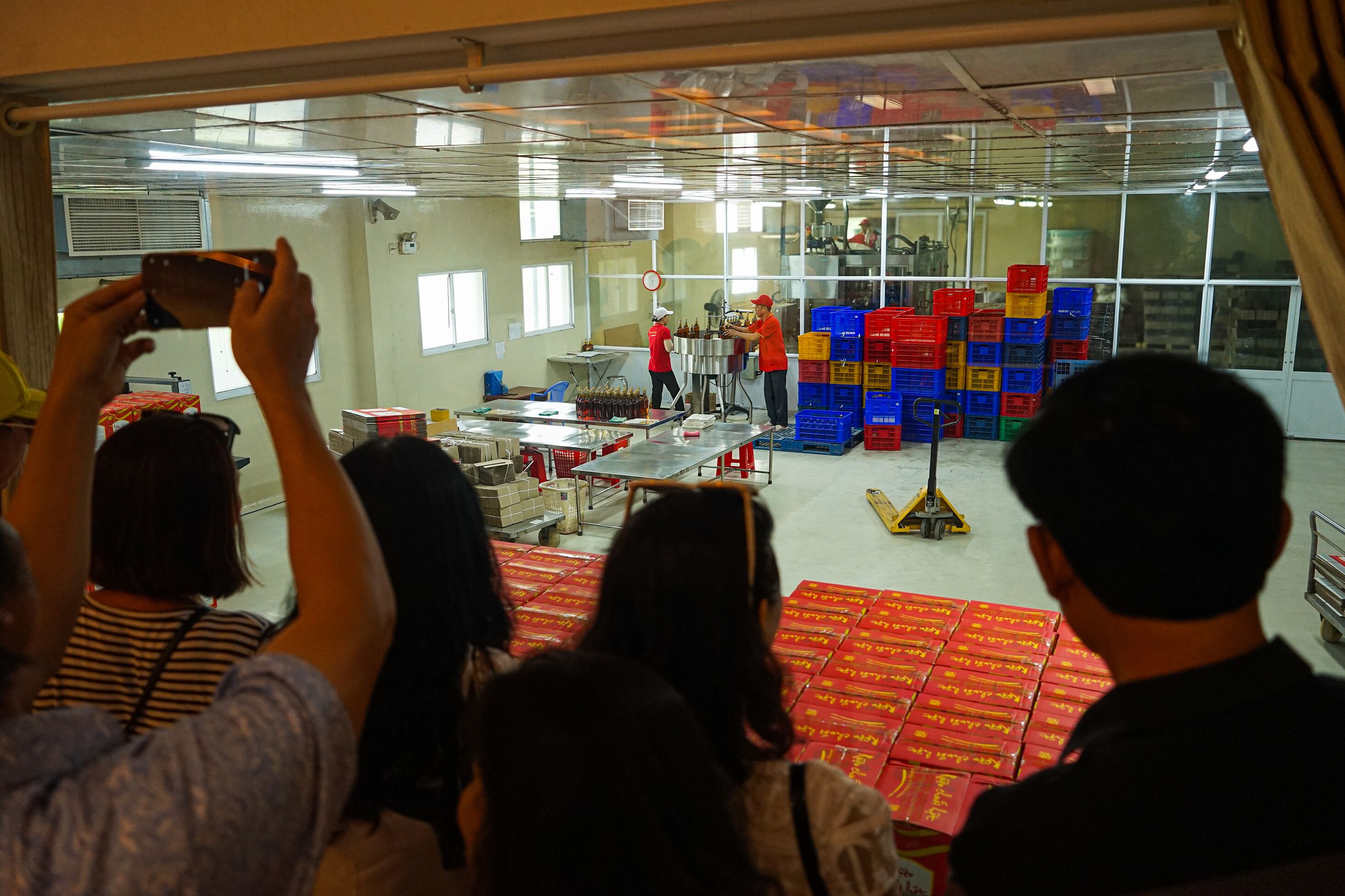 A factory setting with workers and machinery, and stacks of colorful crates in the background.