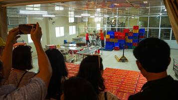 A factory setting with workers and machinery, and stacks of colorful crates in the background.