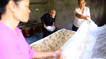 A group of people handling large bags of food in a rustic setting with barrels in the background.