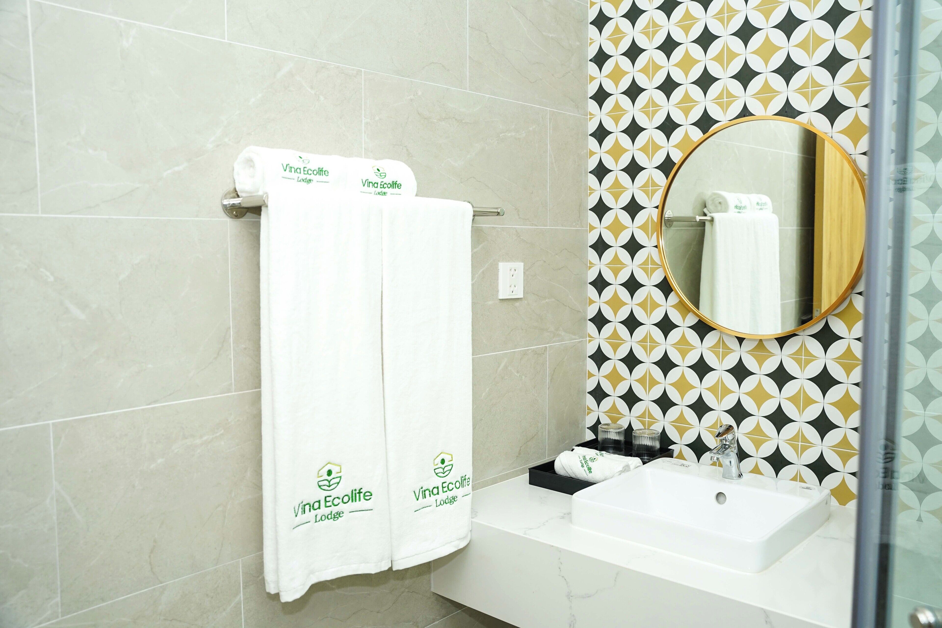Une salle de bain avec deux serviettes blanches suspendues à un porte-serviettes, un lavabo et un miroir avec un cadre en bois.