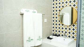 Une salle de bain avec deux serviettes blanches suspendues à un porte-serviettes, un lavabo et un miroir avec un cadre en bois.
