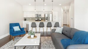 Una sala de estar moderna con un sillón azul, un sofá gris y una mesa de centro con una planta.