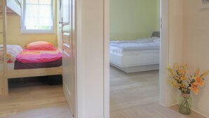 Une chambre avec un lit superposé, une fenêtre et une petite table décorée de fleurs.