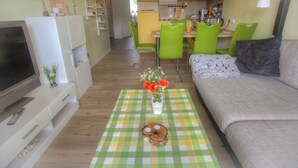 Un salon équipé d’un téléviseur, d’un canapé et d’un coin repas avec des chaises et une table.