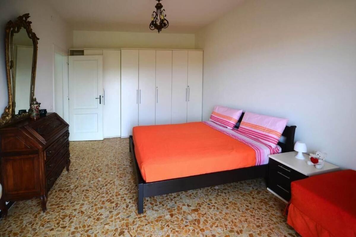 Een slaapkamer met een bed, een dressoir, een garderobe en een spiegel.