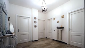 Een gang met witte deuren, een radiator en een kroonluchter.