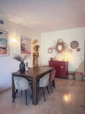 A dining area with a wooden table and chairs, wall art, and decorative wall sconces.