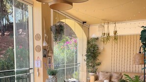 Un comedor con mesa de madera, sillas, plantas colgantes y un sofá.